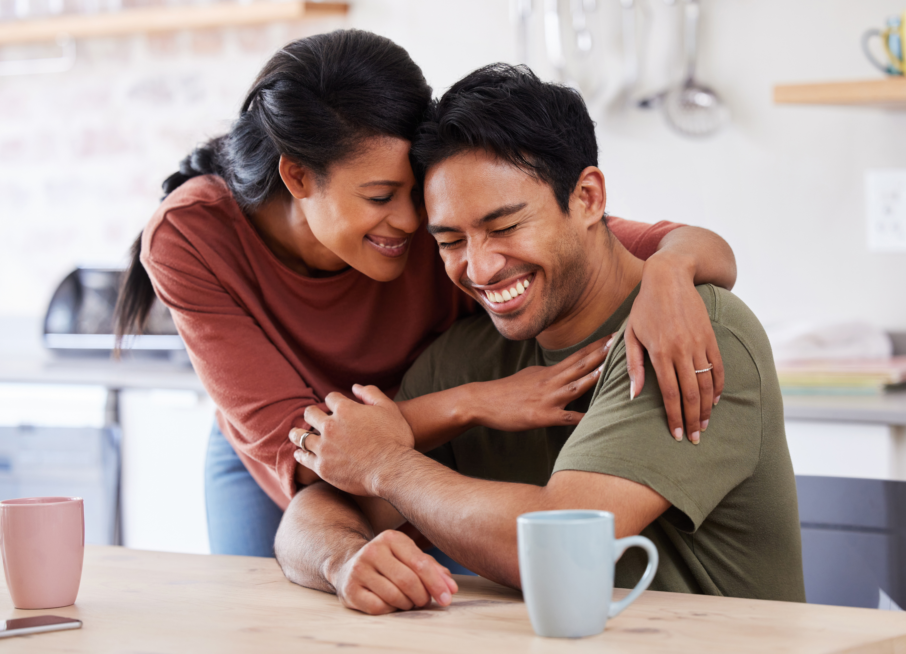 A man and woman smile joyfully while seated together at a table, enjoying each other's company.